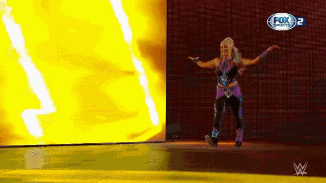 a woman in a purple outfit is dancing on a stage with a fox sports logo in the background