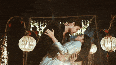 a man is holding a woman in his arms and they are looking into each other 's eyes