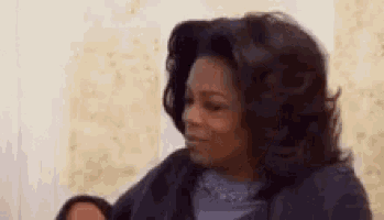 oprah winfrey is holding a baby in her arms and making a face .