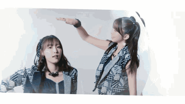 two girls are standing next to each other and one of them is pointing up