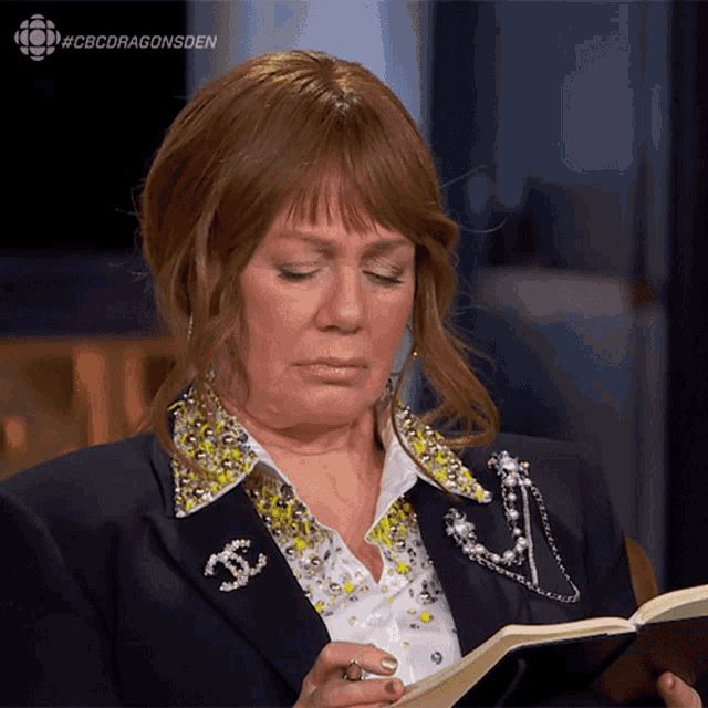a woman reading a book with a chanel brooch