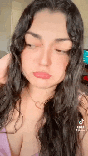 a close up of a woman 's face with her eyes closed and her hand on her head .