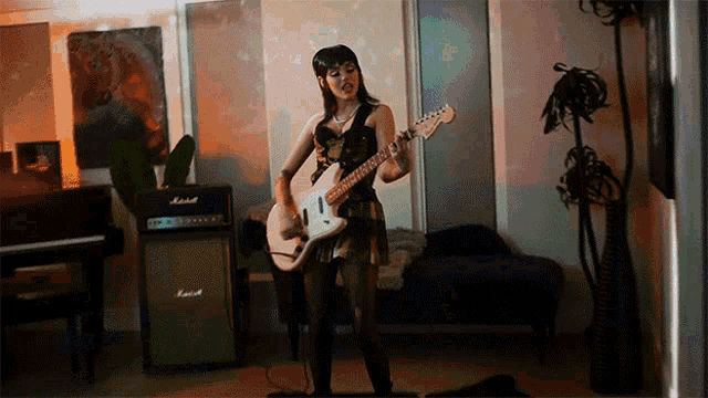 a woman is playing a guitar in front of a marshall amp