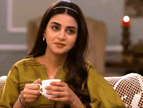 a woman sitting on a couch holding a cup of tea