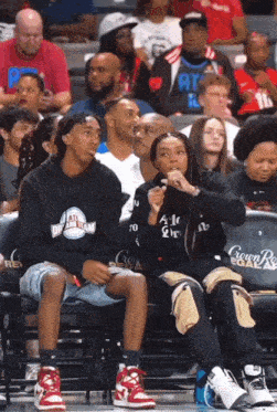 a group of people are sitting in the stands at a basketball game and one of them is wearing an atl dream team sweatshirt