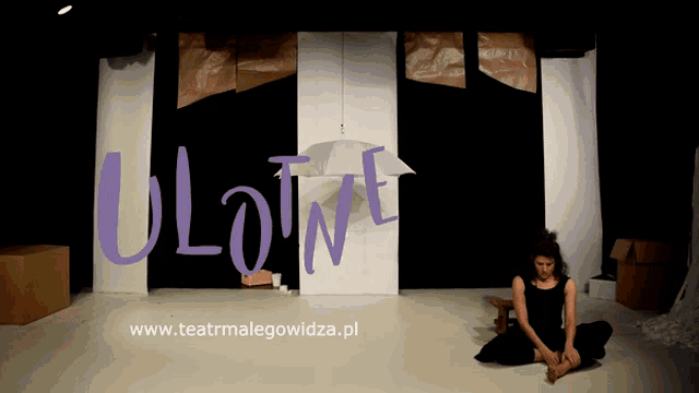 a woman sits on the floor in front of a sign that says " ulowite "