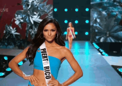 a woman wearing a sash that says puerto rico walks down a runway