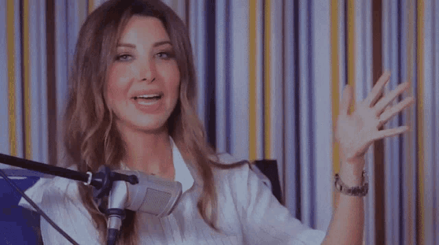 a woman sitting in front of a microphone with a striped wall behind her