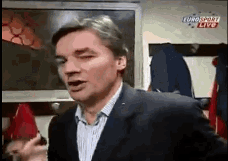 a man in a suit is talking in front of a euro sport live sign