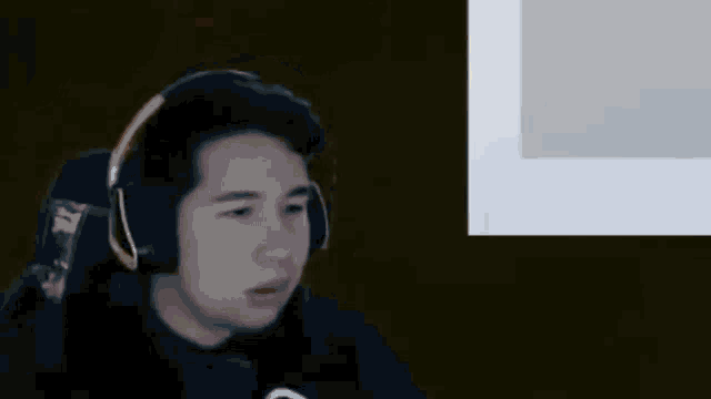 a man wearing headphones is sitting in front of a microphone in a dark room .