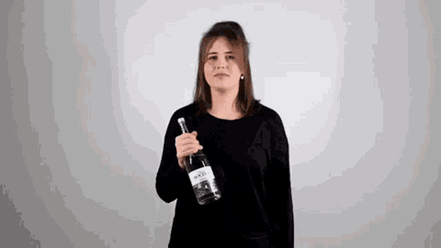 a woman is holding a bottle of alcohol in her hand .