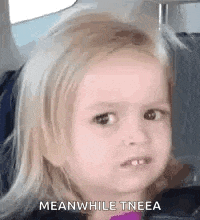 a little girl is making a meanwhile tneea face while sitting in a car seat .