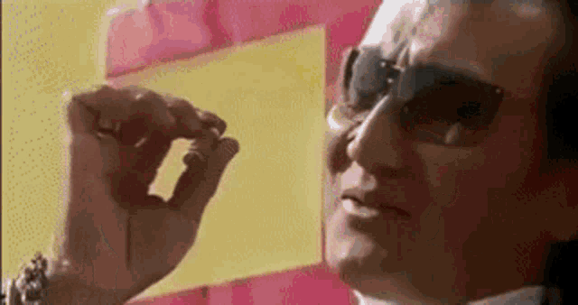 a man wearing sunglasses is holding a piece of paper .
