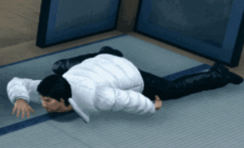 a man in a white jacket is crawling on a mat