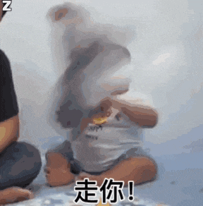 a baby is sitting on a bed with a man kneeling next to it .