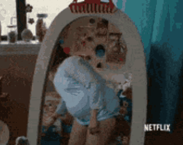 a woman is looking at herself in a mirror with netflix written on it .