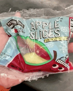 a person holding a bag of apple slices in their hand