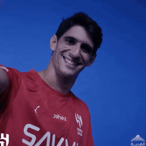 a man wearing a red shirt that says jahez smiles for the camera