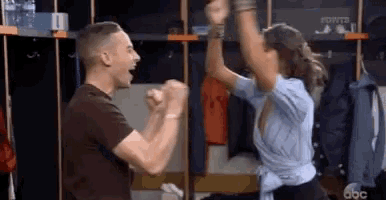 a man and a woman are dancing together in a locker room .