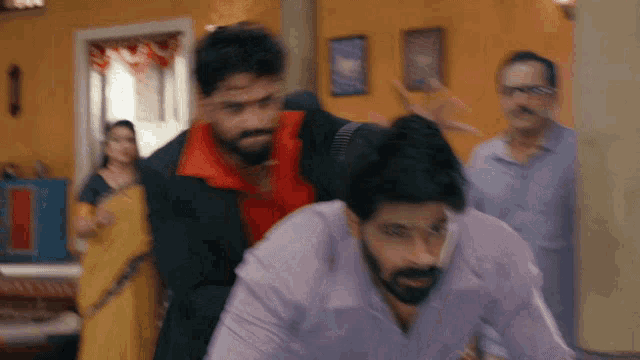 a group of men are standing in a room with a woman in a yellow sari behind them .