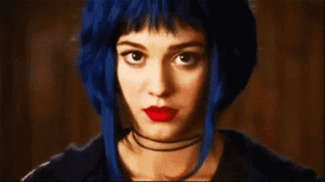 a woman with blue hair and red lipstick is wearing a choker .