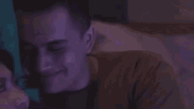 a man and a woman are laying on a bed looking at each other and smiling .