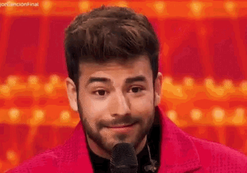 a man with a beard is standing in front of a microphone and smiling