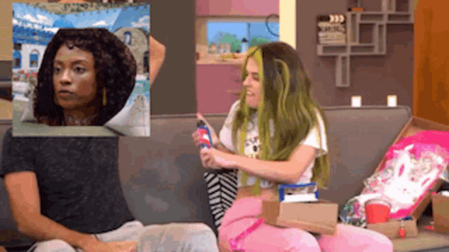 a woman with green hair is sitting on a couch next to another woman