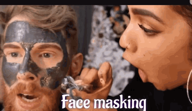 a woman applying a black face mask to a man