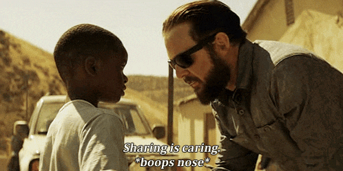 a man wearing sunglasses talks to a young boy and says sharing is caring