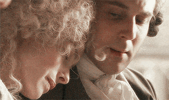 a man and a woman with curly hair are looking at something