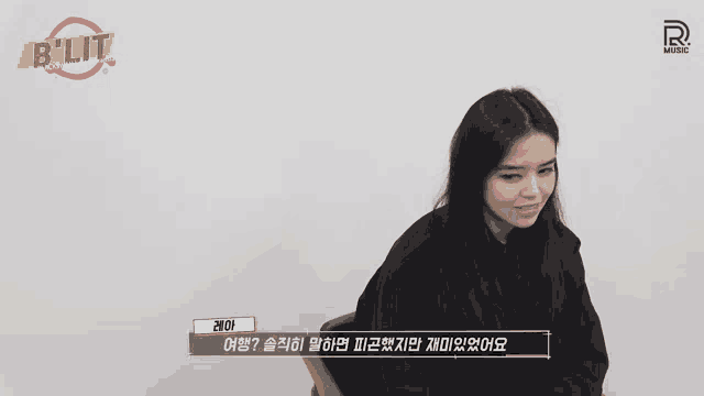 a woman is sitting in front of a b lit sign