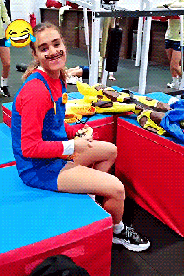 a girl in a mario costume is sitting on a blue cushion