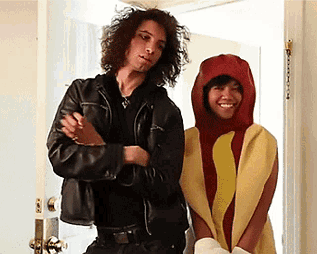 a man in a leather jacket and a woman in a hot dog costume are standing next to each other