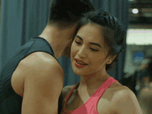 a man kissing a woman on the cheek in a gym