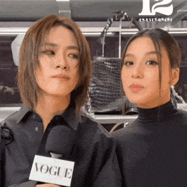 two women are standing next to each other with a vogue microphone in front of them
