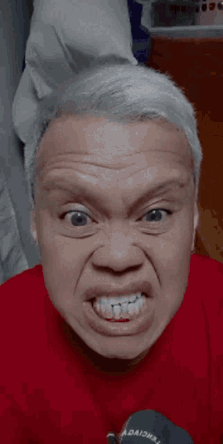 a man wearing a red shirt with the word adaions on it makes a funny face