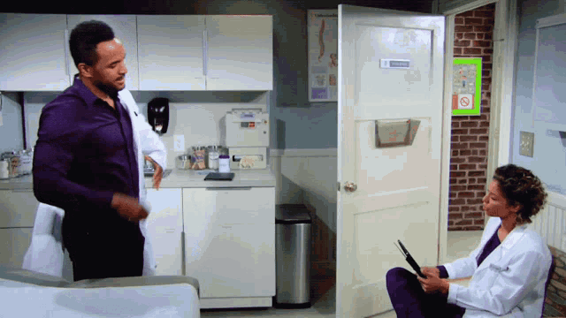 a man in a purple shirt stands next to a woman in a white coat