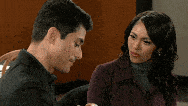 a man and a woman are sitting next to each other and the woman is holding a cup