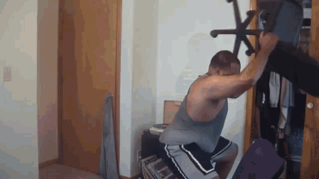 a man is squatting down while holding a chair