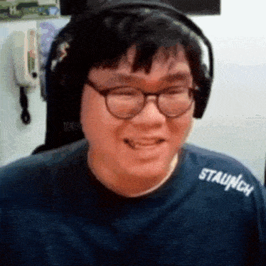 a man wearing glasses and headphones is smiling while wearing a blue shirt .