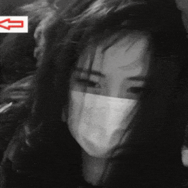 a black and white photo of a girl wearing a mask