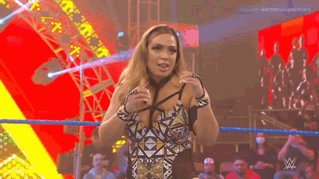 a woman is standing in a wrestling ring holding her bra .