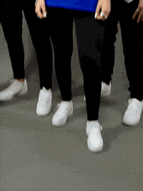 a group of people wearing white shoes and black pants are walking
