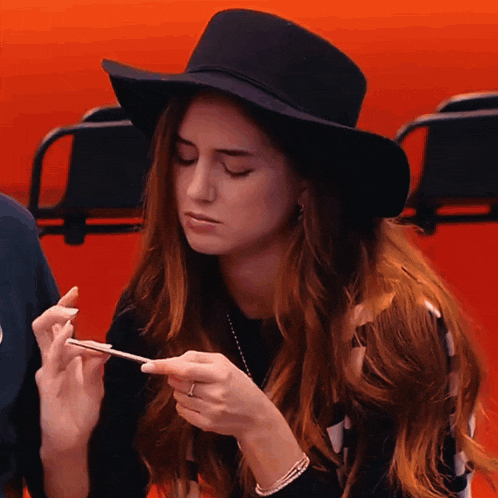 a woman wearing a black hat is holding a cell phone in her hand