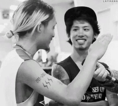 a man with a tattoo on his arm is standing next to another man .
