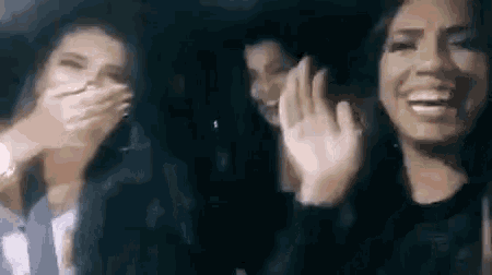 two women are laughing and clapping in a car .
