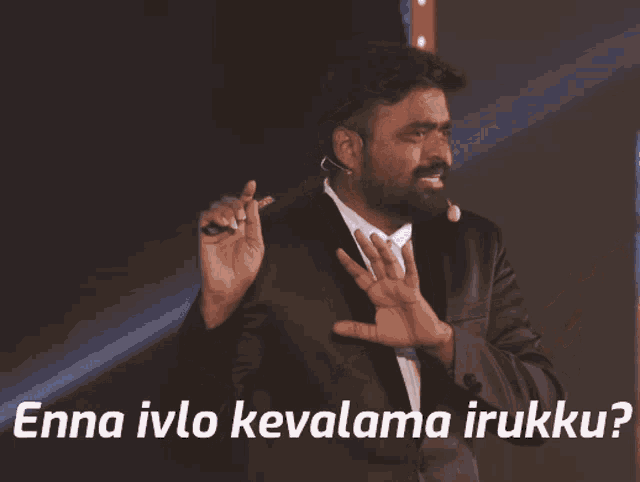 a man in a suit speaking into a microphone with the words enna ivo kevalama irukku written below him