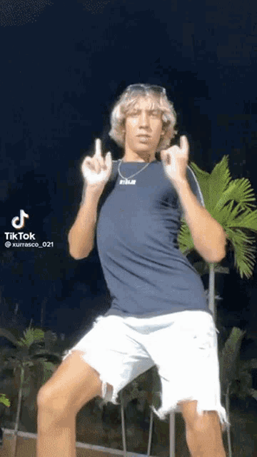 a man in a blue shirt and white shorts is doing a tik tok
