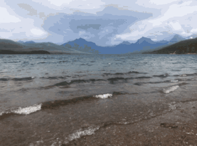 a lake with mountains in the background and a cloudy sky